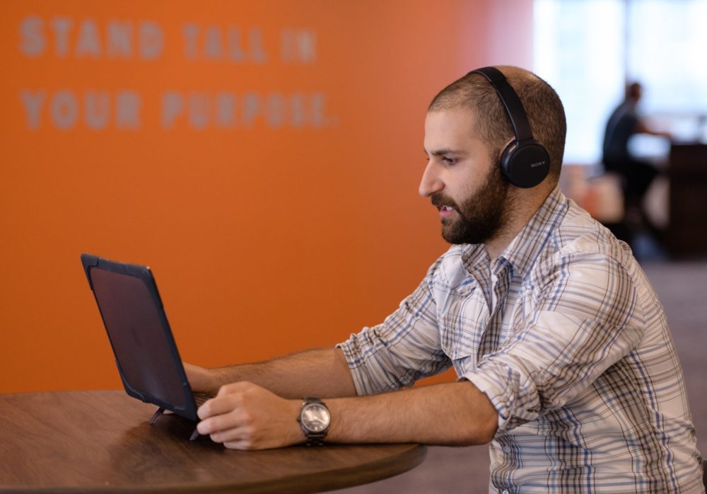 A man wearing headphone looking at his computer