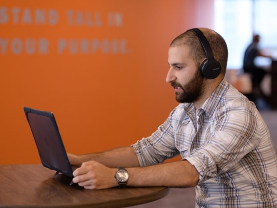 A man wearing headphone looking at his computer