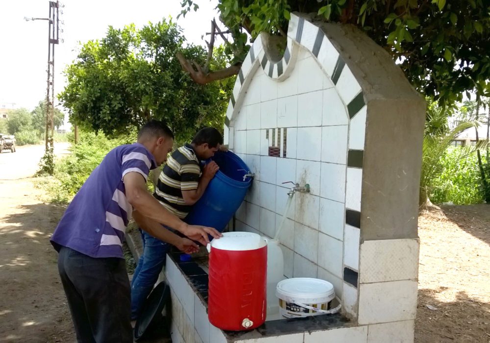 Egyptians filling water buckets at fountain
